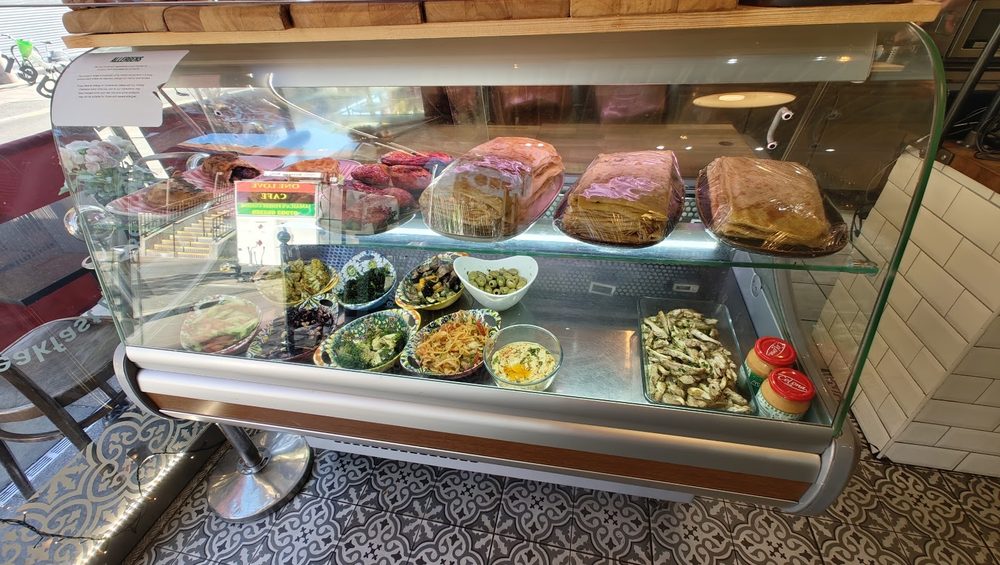 A glass deli cabinet filled with salads, cakes and pastries.