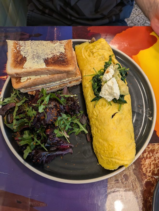 A rolled omelette with feta, salad leaves and toast.