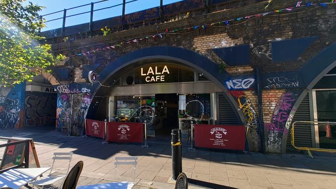 The cafe's arch shopfront with pavement seating on Brixton Station Road.