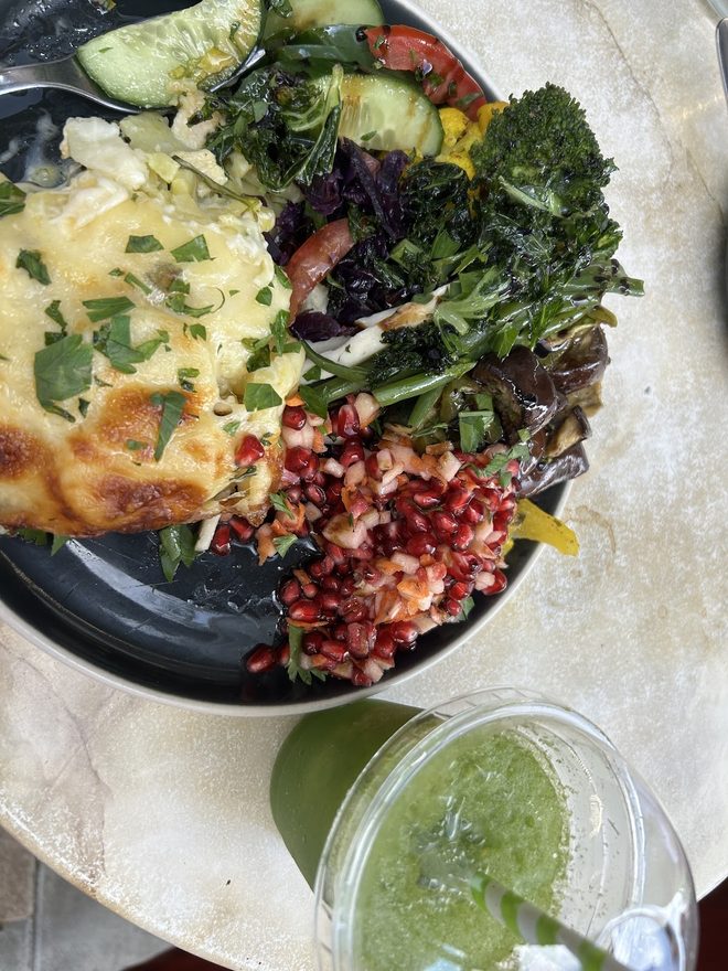 An overhead mezze plate with a green juice.