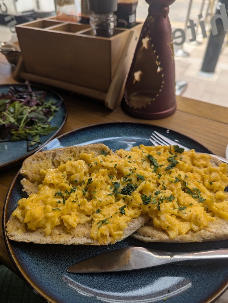 Scrambled eggs with herbs served on flatbread on a blue plate.