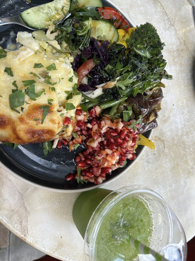 A mezze plate of flatbread, kale, feta, pomegranate and beetroot salad with a green juice.