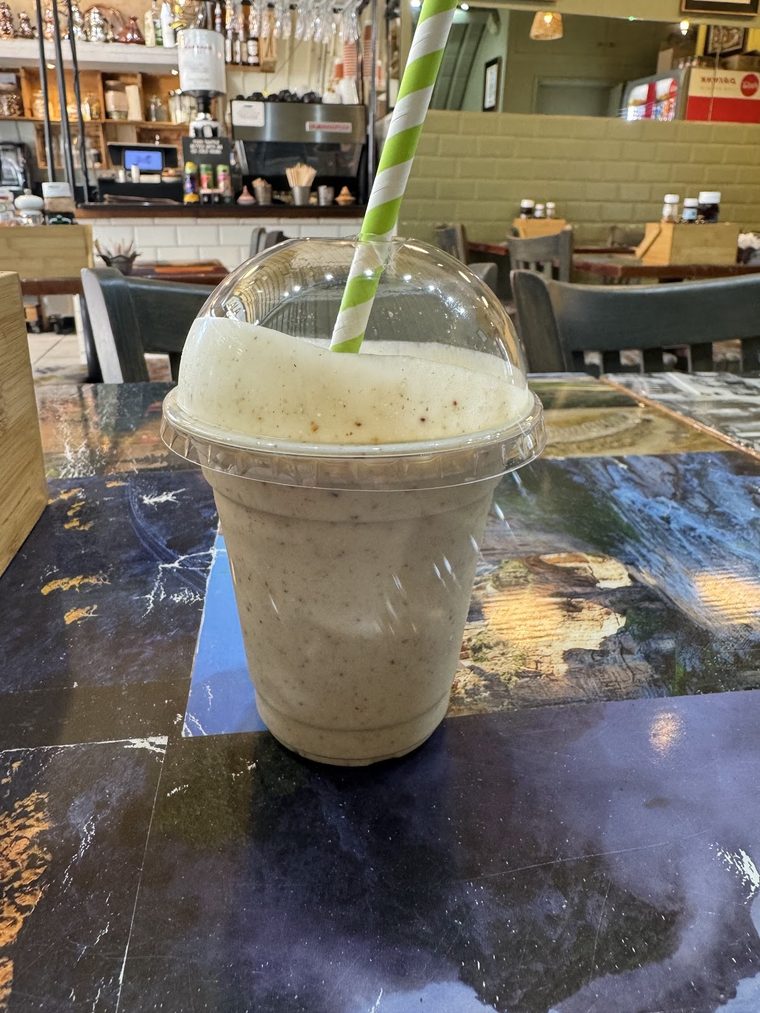 A takeaway smoothie in a cup with a paper straw on a marble table.